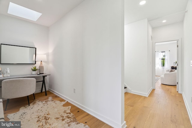 office space featuring a skylight and light hardwood / wood-style flooring