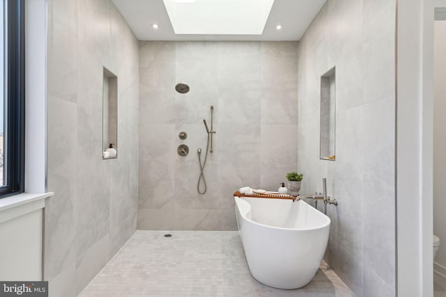 bathroom featuring a skylight, independent shower and bath, tile walls, and tile patterned floors