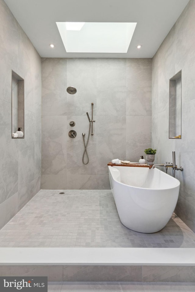 bathroom with shower with separate bathtub, tile walls, and a skylight