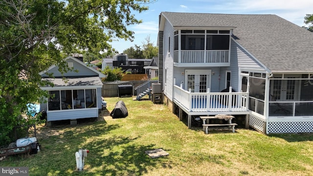 rear view of property with a wooden deck, a sunroom, a yard, and an outdoor structure