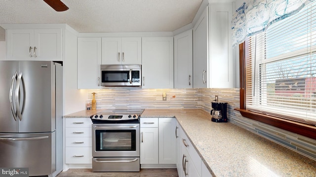 kitchen with tasteful backsplash, light stone counters, white cabinets, and stainless steel appliances