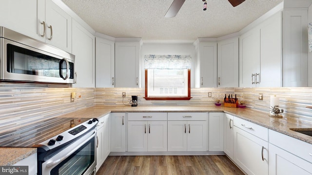 kitchen with white cabinets, backsplash, and stainless steel appliances