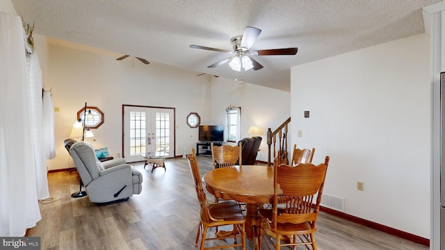 dining space featuring ceiling fan, french doors, a textured ceiling, and light wood-type flooring