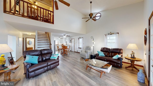 living room featuring a high ceiling, light wood-type flooring, and ceiling fan