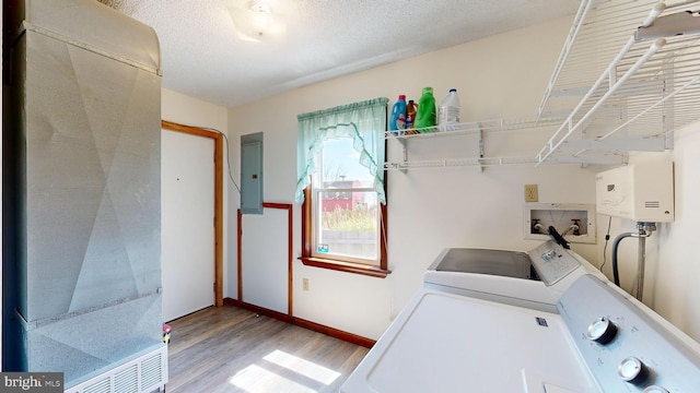 laundry room with tankless water heater, light hardwood / wood-style flooring, independent washer and dryer, electric panel, and a textured ceiling