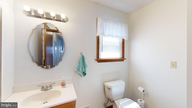 bathroom featuring vanity, a textured ceiling, and toilet