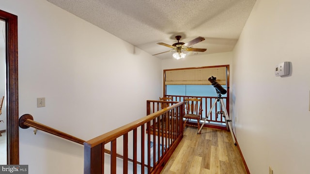 hall with a textured ceiling and light hardwood / wood-style flooring