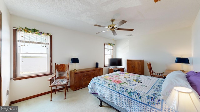 bedroom featuring a textured ceiling, ceiling fan, and light carpet