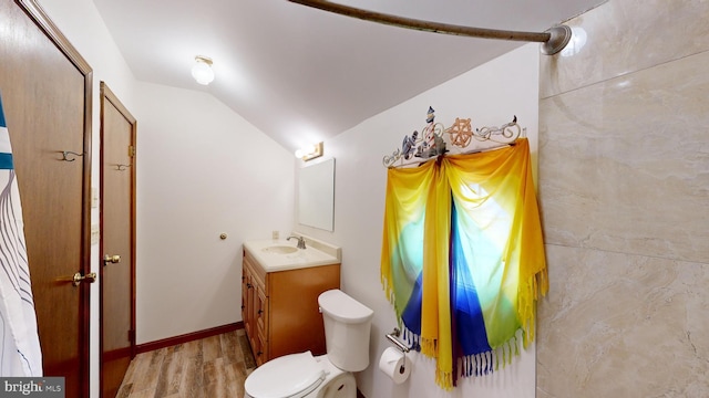 bathroom featuring hardwood / wood-style floors, vanity, vaulted ceiling, and toilet