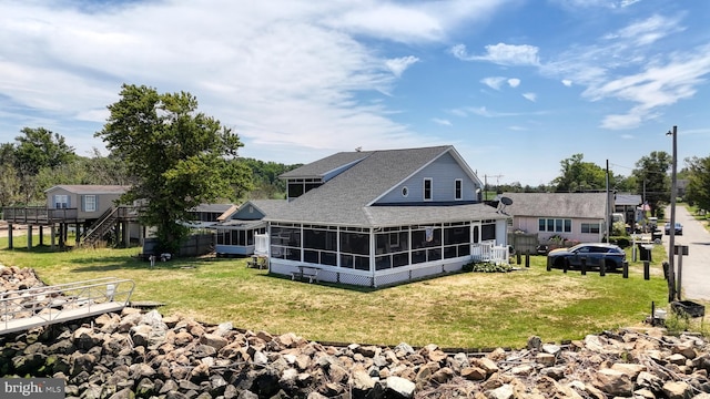 rear view of property featuring a lawn and a sunroom