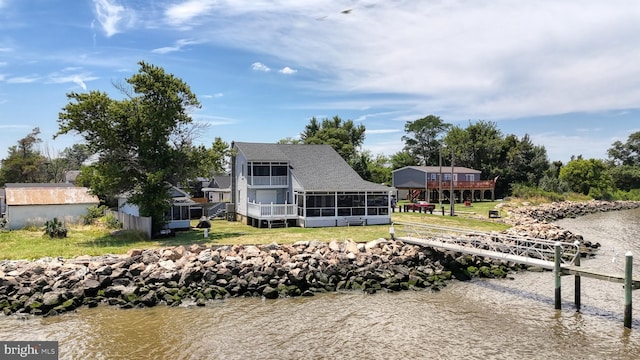 back of property featuring a lawn, a sunroom, and a water view