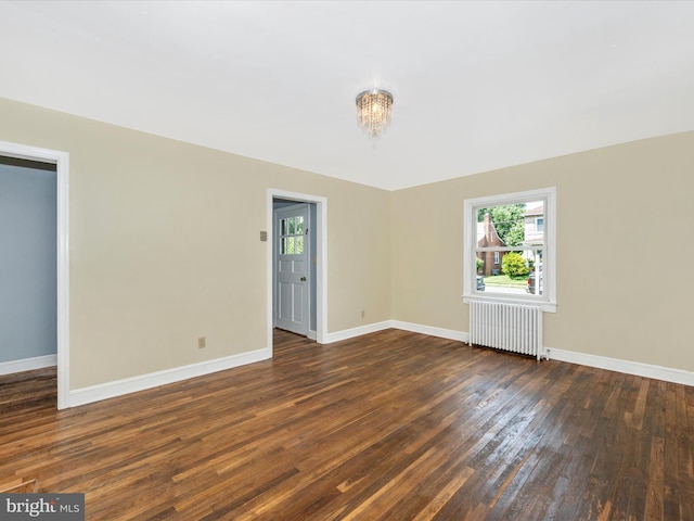 unfurnished room with radiator, dark hardwood / wood-style flooring, and a chandelier