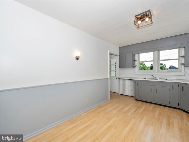 kitchen featuring radiator, sink, gray cabinetry, and light hardwood / wood-style floors