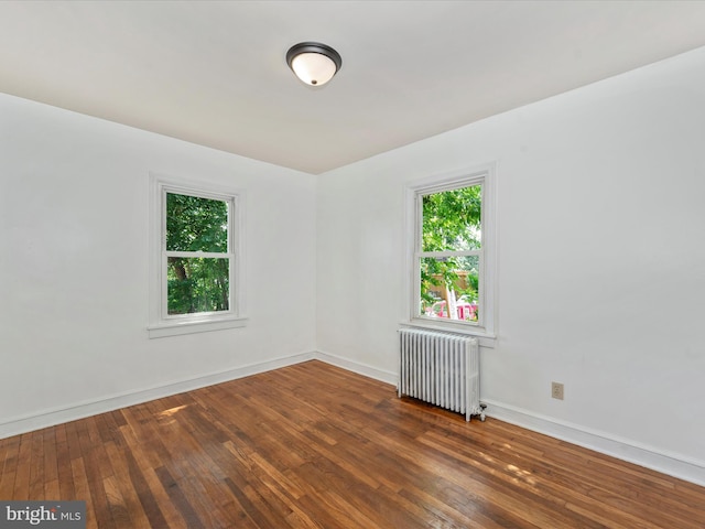 unfurnished room featuring dark hardwood / wood-style floors and radiator heating unit