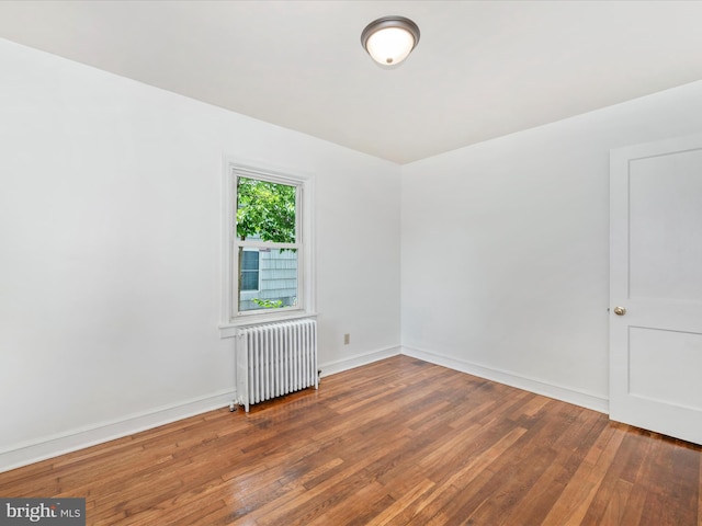 unfurnished room featuring radiator and dark hardwood / wood-style floors