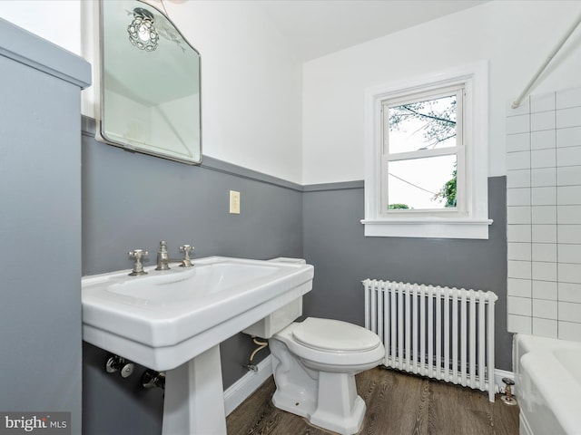 bathroom featuring toilet, sink, a bathing tub, hardwood / wood-style flooring, and radiator