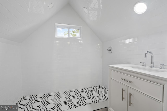 bathroom with vanity, tiled shower, tile walls, and lofted ceiling