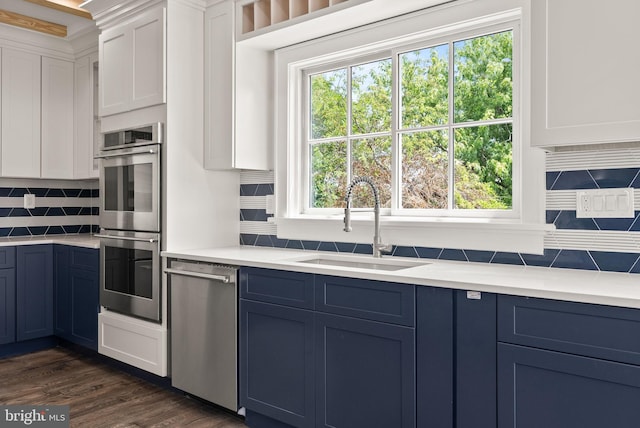 kitchen featuring white cabinetry, stainless steel appliances, blue cabinetry, and dark wood-type flooring