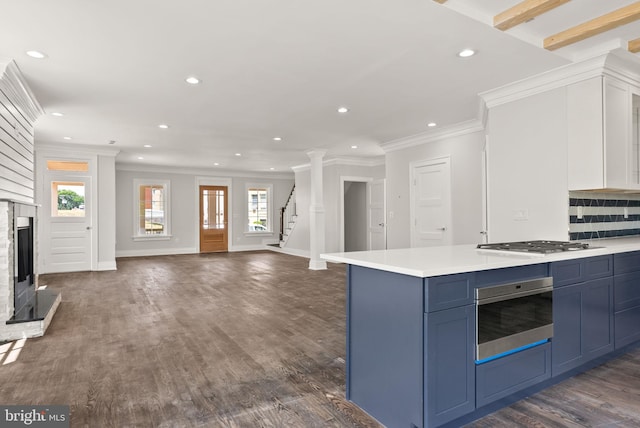 kitchen with crown molding, backsplash, dark hardwood / wood-style floors, appliances with stainless steel finishes, and blue cabinetry