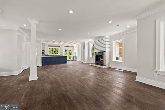 unfurnished living room with decorative columns, dark wood-type flooring, and crown molding