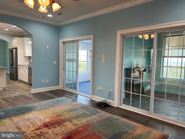 doorway featuring crown molding, ceiling fan, and dark wood-type flooring