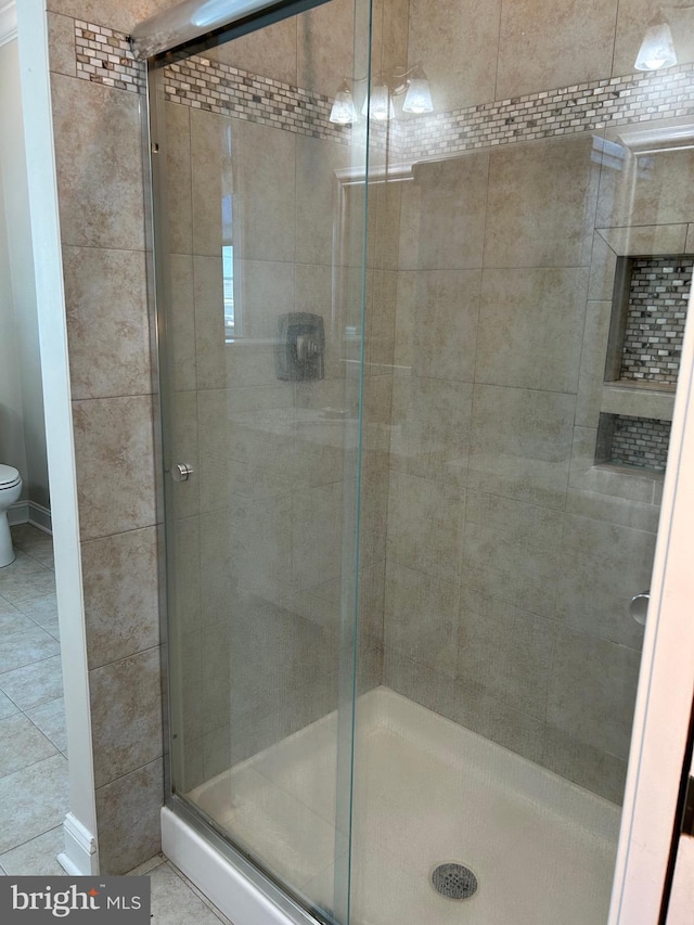 bathroom featuring tile patterned floors, toilet, and walk in shower