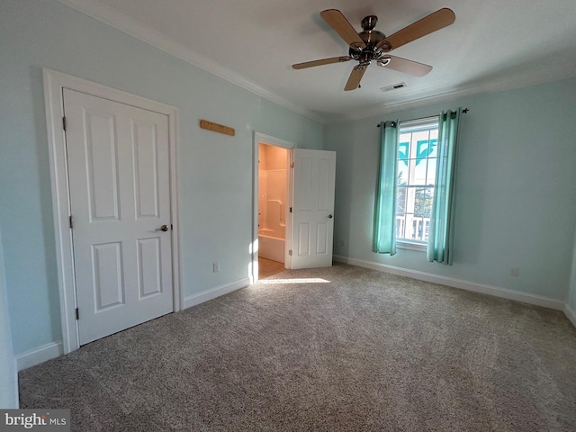 unfurnished bedroom with carpet flooring, ensuite bath, ceiling fan, and ornamental molding