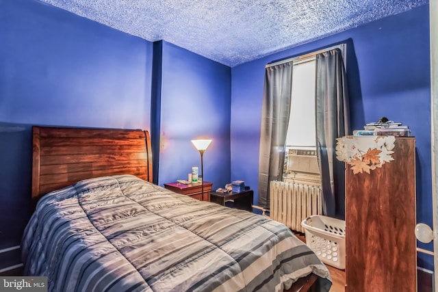 bedroom with cooling unit, radiator heating unit, and a textured ceiling