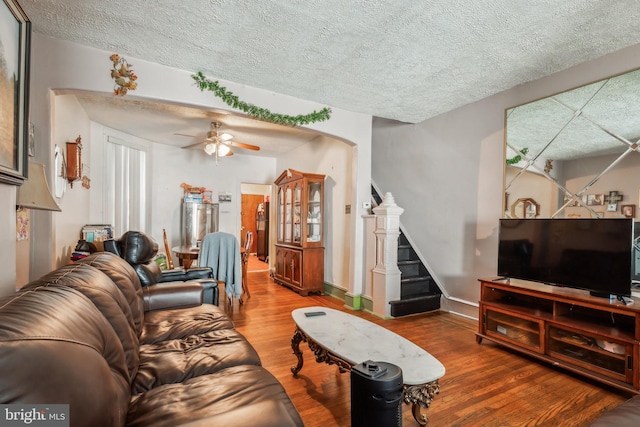 living room with ceiling fan, wood-type flooring, and a textured ceiling