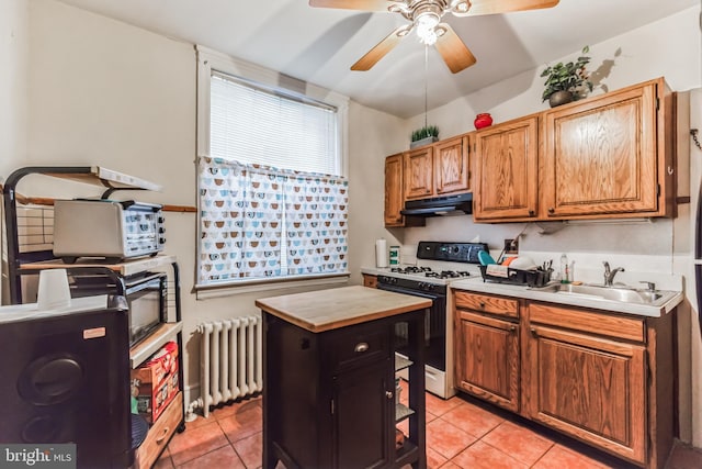 kitchen featuring gas range gas stove, radiator heating unit, sink, light tile patterned flooring, and a kitchen island