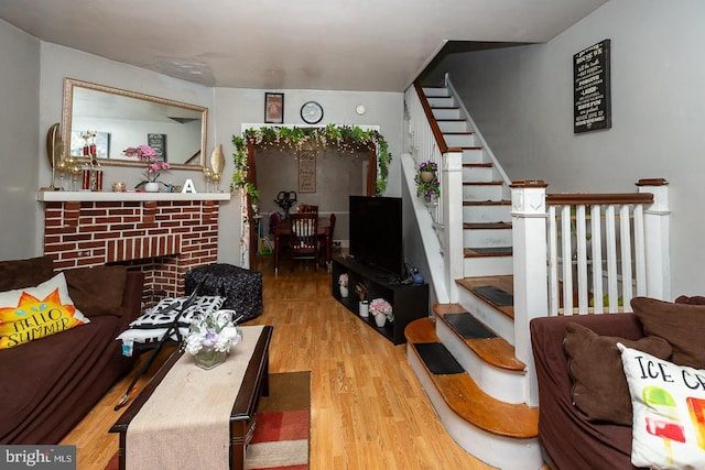 living room with a brick fireplace and hardwood / wood-style flooring