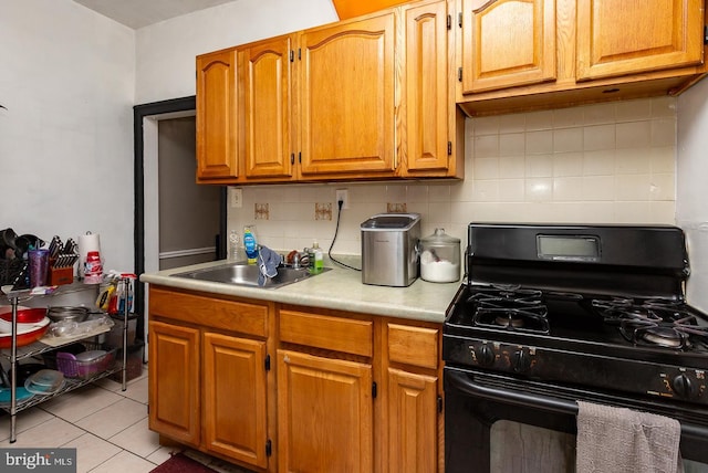 kitchen with tasteful backsplash, sink, light tile patterned floors, and black gas range oven