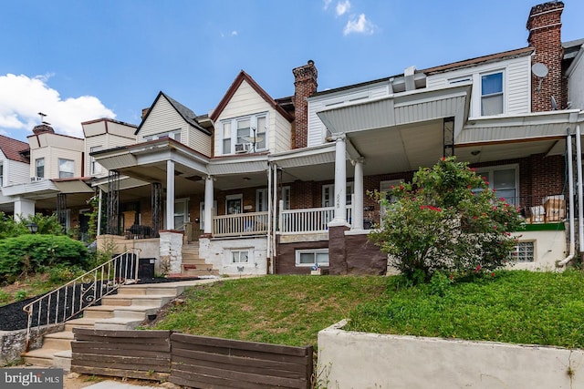 multi unit property featuring covered porch and a front yard