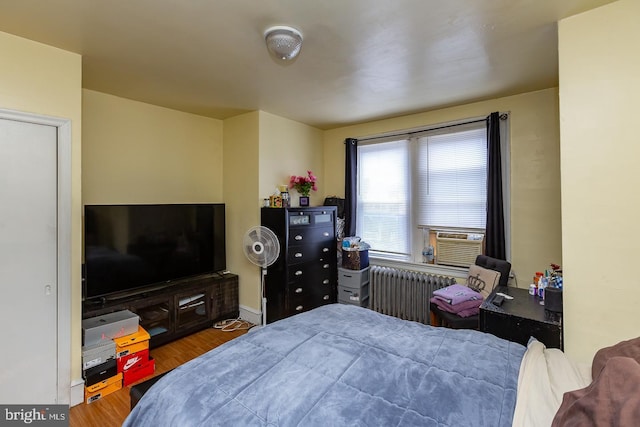 bedroom with radiator, hardwood / wood-style floors, and cooling unit