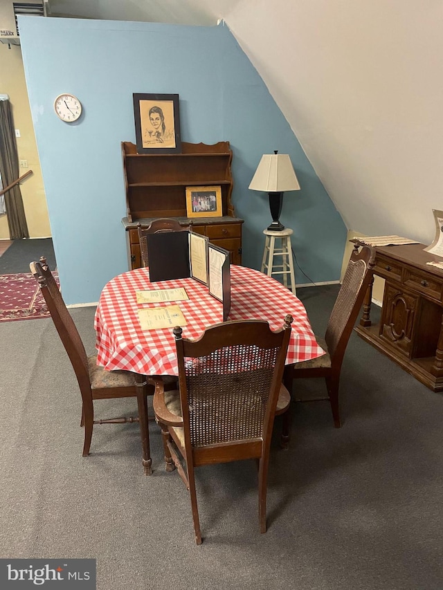 dining area featuring carpet and vaulted ceiling