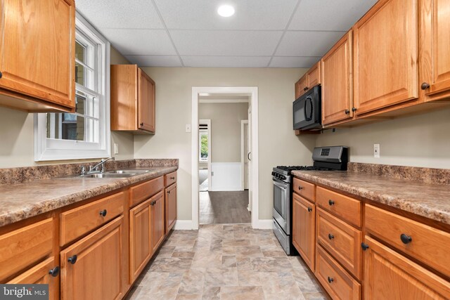 kitchen featuring gas range, a drop ceiling, and sink