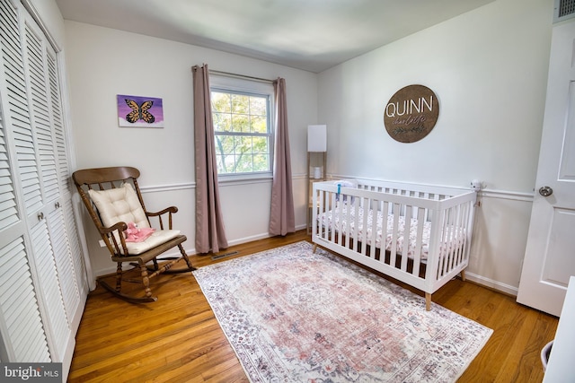 bedroom featuring a closet, a nursery area, and wood-type flooring