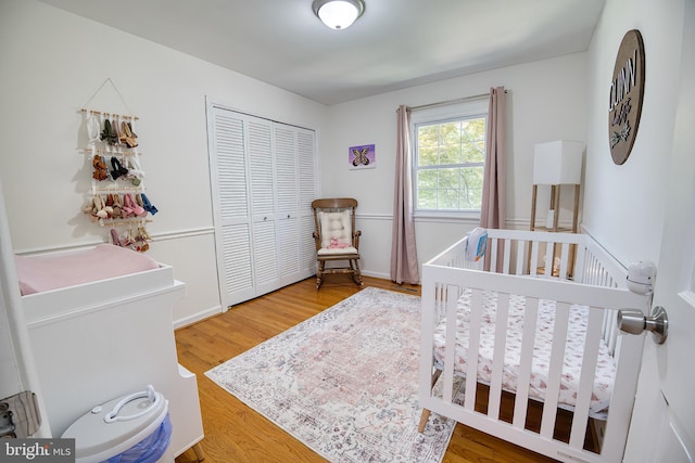 bedroom with hardwood / wood-style flooring, a closet, and a crib