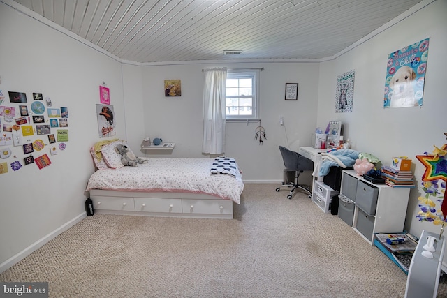 bedroom with ornamental molding, wood ceiling, and carpet floors