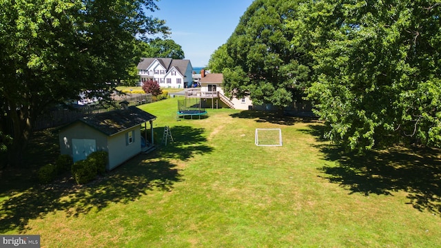 view of yard featuring a wooden deck, an outdoor structure, and a trampoline