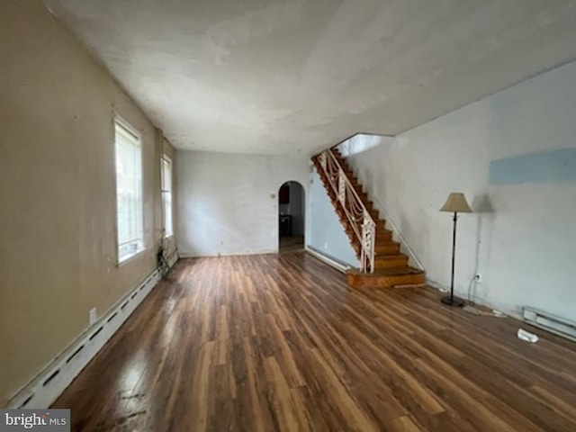 unfurnished living room featuring baseboard heating and dark hardwood / wood-style flooring