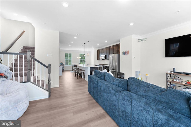 living room featuring sink, light hardwood / wood-style flooring, and ornamental molding