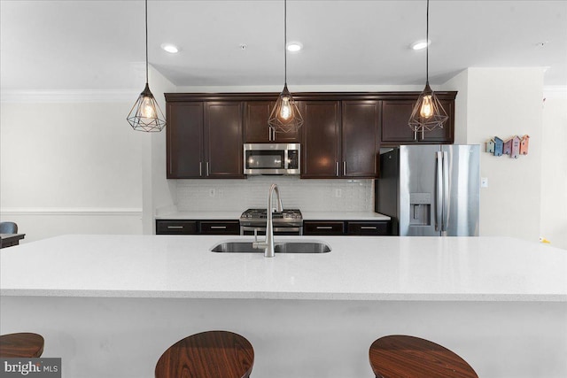 kitchen featuring sink, stainless steel appliances, backsplash, decorative light fixtures, and a breakfast bar area