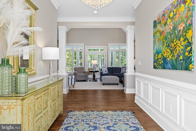 corridor with ornate columns, a notable chandelier, dark hardwood / wood-style floors, and ornamental molding