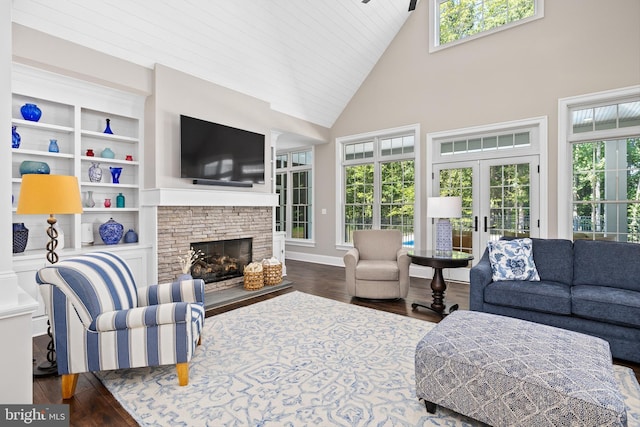 living room with french doors, dark hardwood / wood-style flooring, a stone fireplace, and a high ceiling