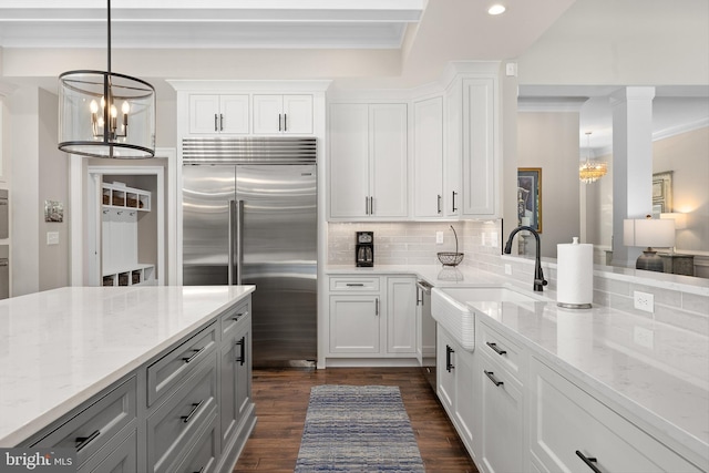 kitchen with white cabinets, sink, light stone countertops, a notable chandelier, and stainless steel appliances