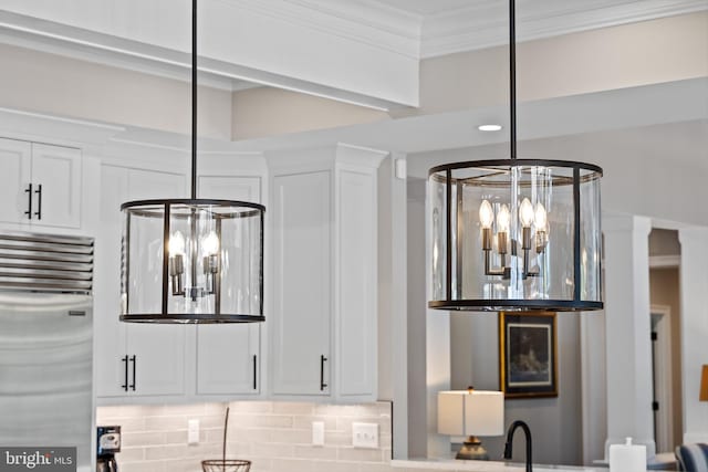 interior details with white cabinetry, stainless steel fridge, and a notable chandelier