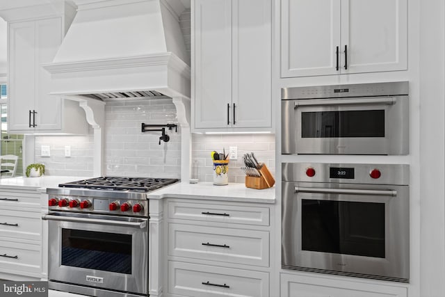 kitchen featuring white cabinets, custom exhaust hood, backsplash, and stainless steel appliances