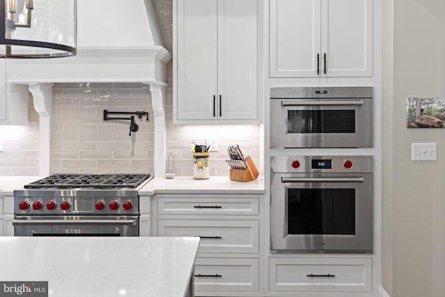 kitchen with white cabinets, backsplash, light stone counters, and stainless steel appliances