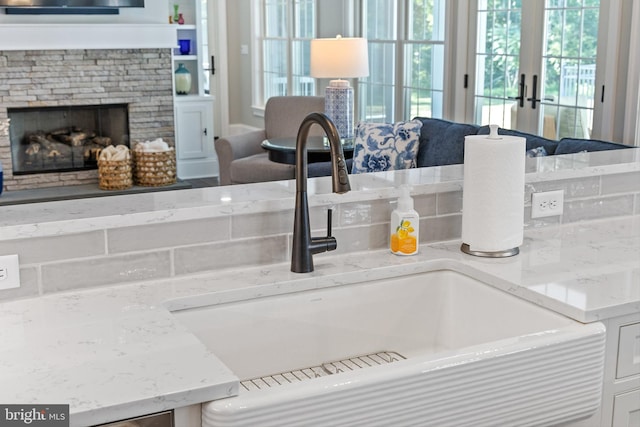 interior details with light stone countertops, french doors, a fireplace, and sink